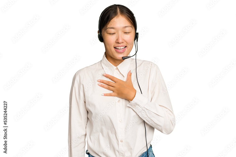 Telemarketer asian woman working with a headset isolated on green chroma background laughs out loudly keeping hand on chest. Telemarketer asian woman working with a headset isolated on green chroma background laughs out loudly keeping hand on chest.