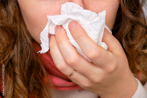 Obraz na plátně A sick woman blows her nose in a napkin, a runny nose