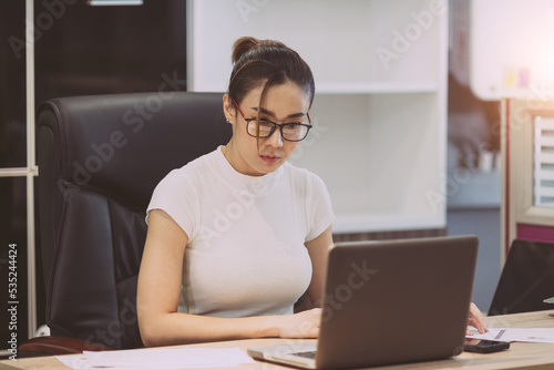asian beautiful woman focus on business work. busy female worker working overtime try to find information on paper sheet and sticky notes on table. occupation office woman overwork alone at workplace