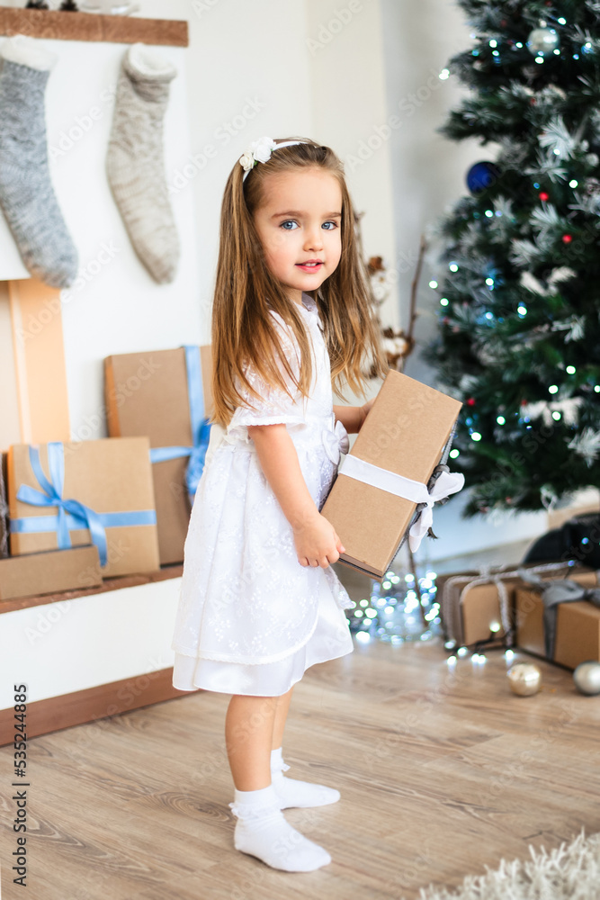 A child girl in a decorated Christmas room holds a New Year's gift in her hands. A child girl in a decorated Christmas room holds a New Year's gift in her hands.