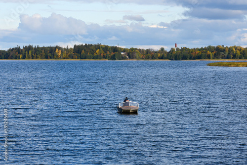 beautiful lake view with fishing boat and water tower in the distance in autumn on a sunny day