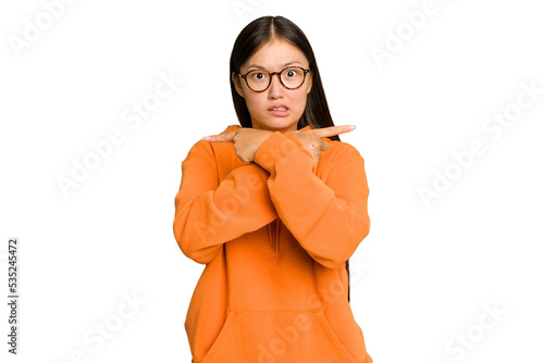 Young Asian woman isolated on green chroma background points sideways, is trying to choose between two options.