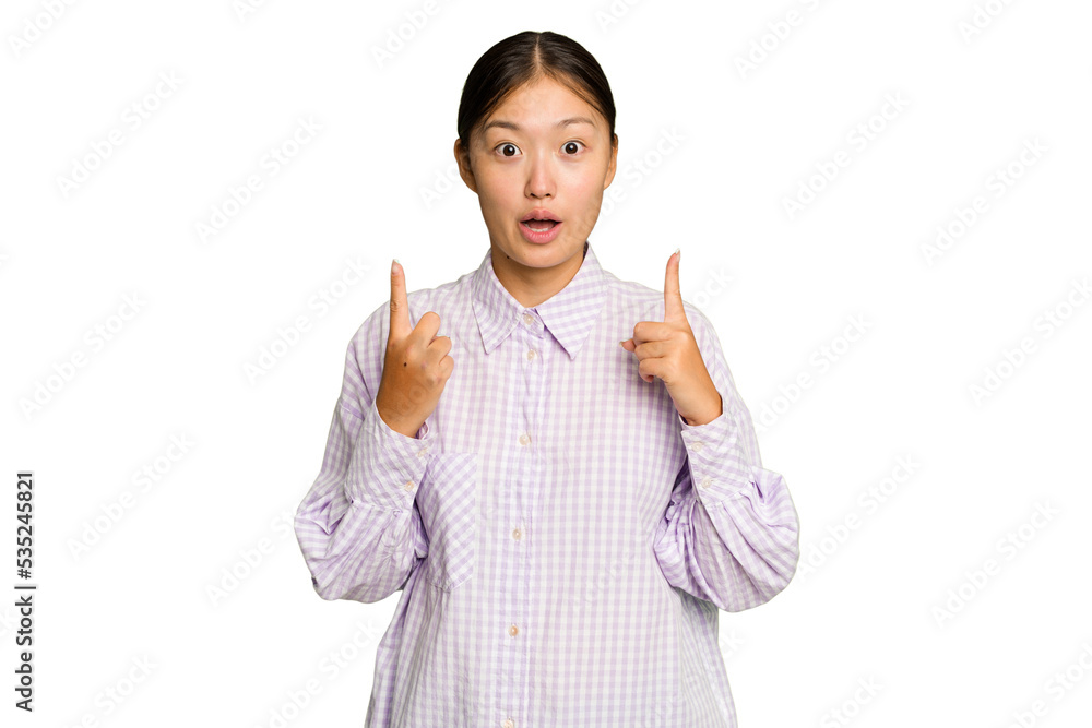 Young Asian woman isolated on green chroma background pointing upside with opened mouth.