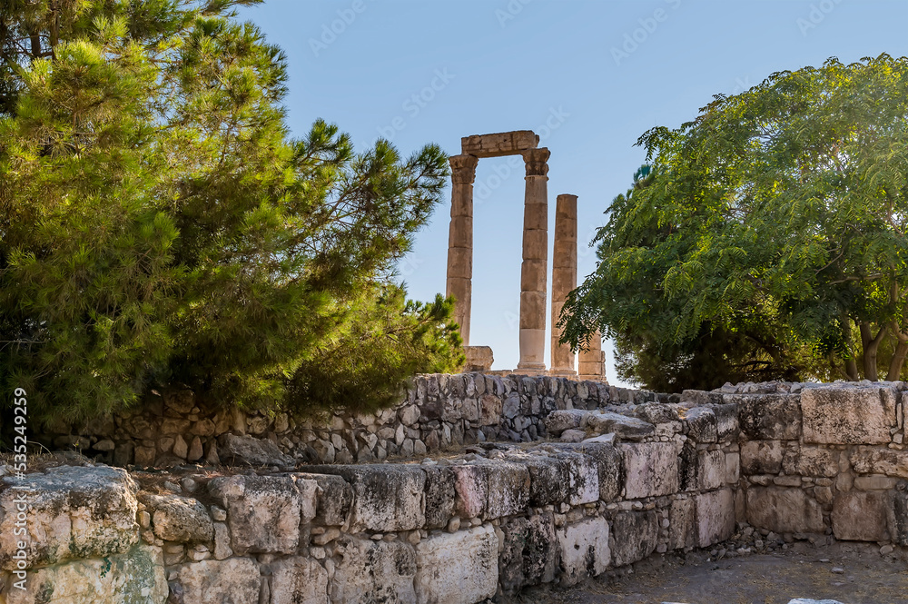 A glimpse through trees of the Temple of Hercules in the citadel in Amman, Jordan in summertime