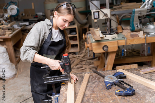 Portrait of a female carpenter using tools for making furniture in a furniture factory. with modern tools