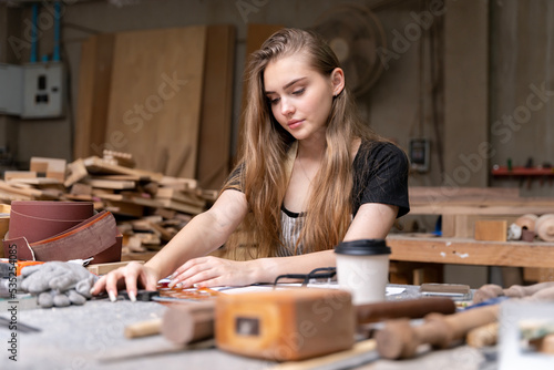 Portrait of a female carpenter drawing on paper for designing and building furniture in a furniture factory. with modern tools