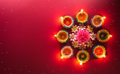 Happy Diwali - Clay Diya lamps lit during Diwali, Hindu festival of lights celebration. Colorful traditional oil lamp diya on red background
