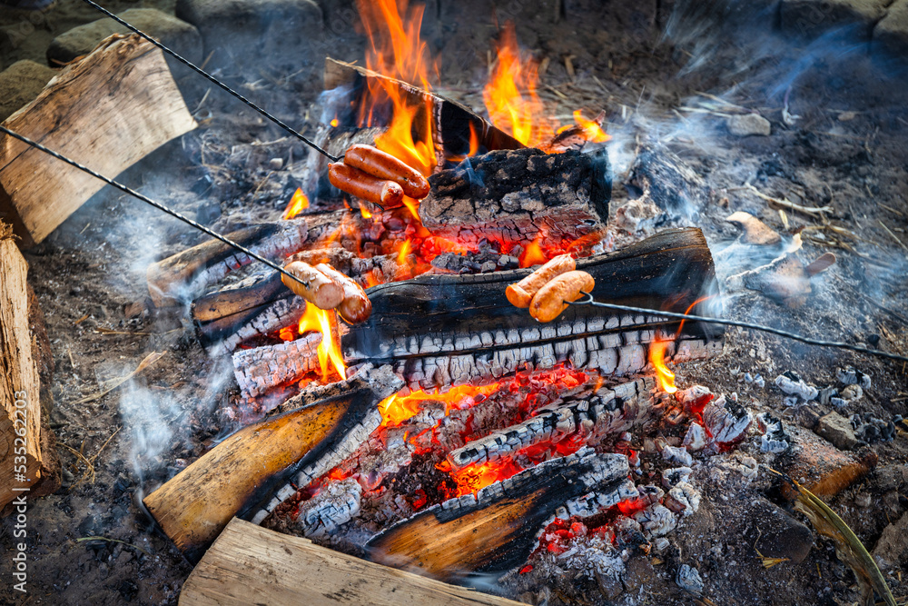 Traditional barbecue sausages on a stick roasted on a campfire Traditional barbecue sausages on a stick roasted on a campfire