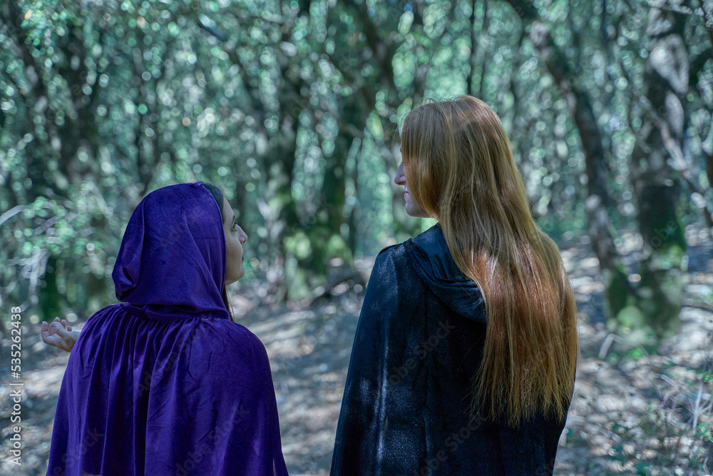 Two young witches searching for objects in the woods
