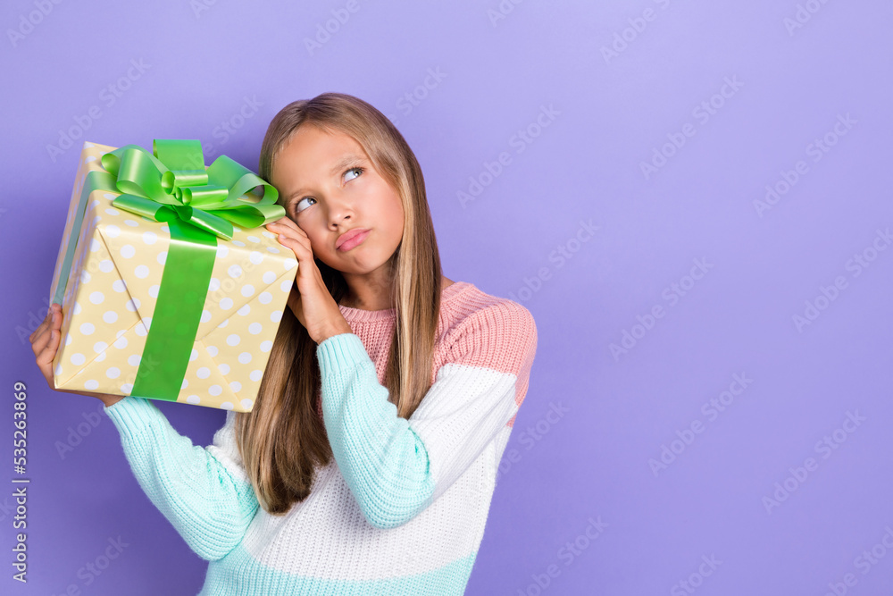 Photo of concentrated uncertain unsure girl hold birthday package look up empty space decide isolated on purple color background Photo of concentrated uncertain unsure girl hold birthday package look up empty space decide isolated on purple color background