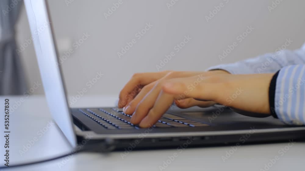 Girl typing text on laptop keyboard. Young woman working on modern notebook computer Girl typing text on laptop keyboard. Young woman working on modern notebook computer