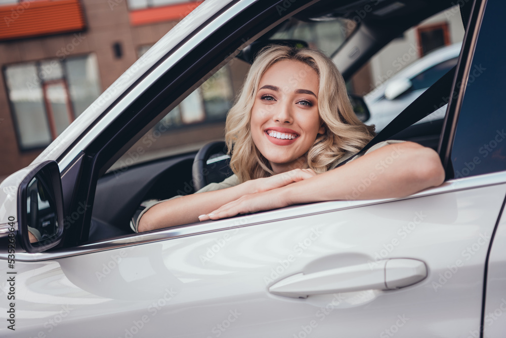 Photo of friendly satisfied lady sitting car front seat look camera through window street outdoors
