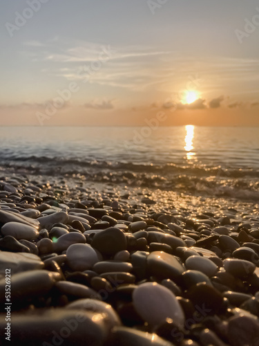 View of the sea and sun rising above the stones in Cirali, Antalya, Turkey. Selective focus. © jineps