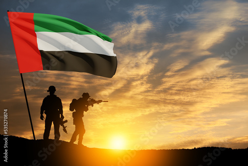 Silhouettes of soldiers with the flag of UAE against sunset or sunrise. Concept of national holidays. Commemoration Day.