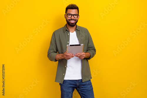 Photo of funny cheerful man wear khaki shirt spectacles texting modern device isolated yellow color background