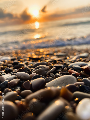View of the sea and sun rising above the stones in Cirali, Antalya, Turkey. Selective focus.