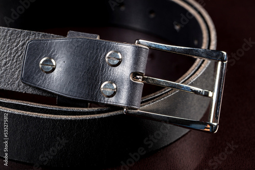 Black leather belt on a dark background. Leather products.