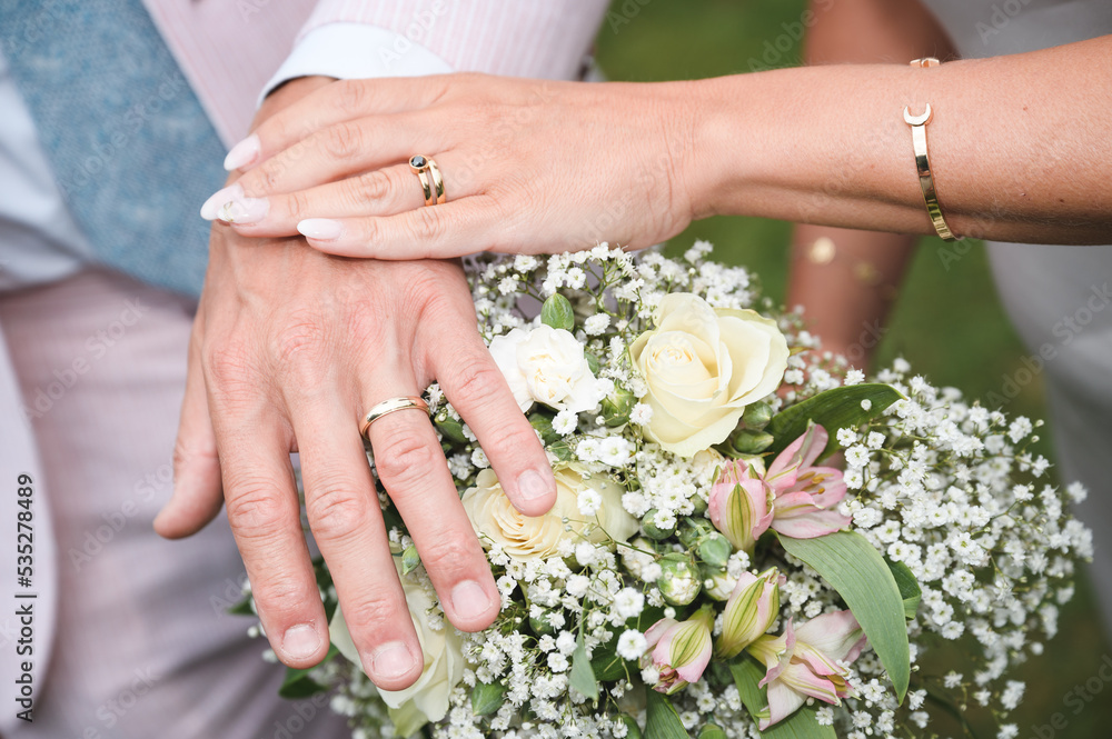 Bride and Groom hands over wedding flowers showing their marriage rings Bride and Groom hands over wedding flowers showing their marriage rings