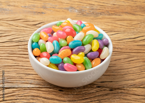 Colorful jelly beans in a bowl over wooden table