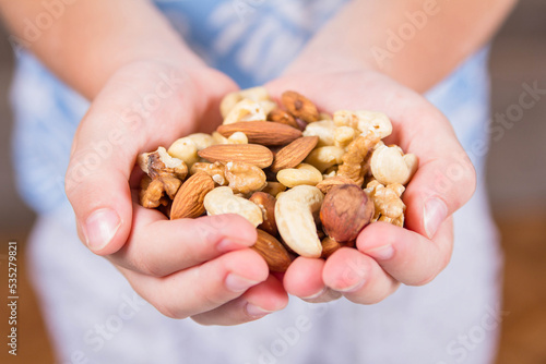 Сhildren's palms filled with shelled almonds, walnuts, cashew nuts