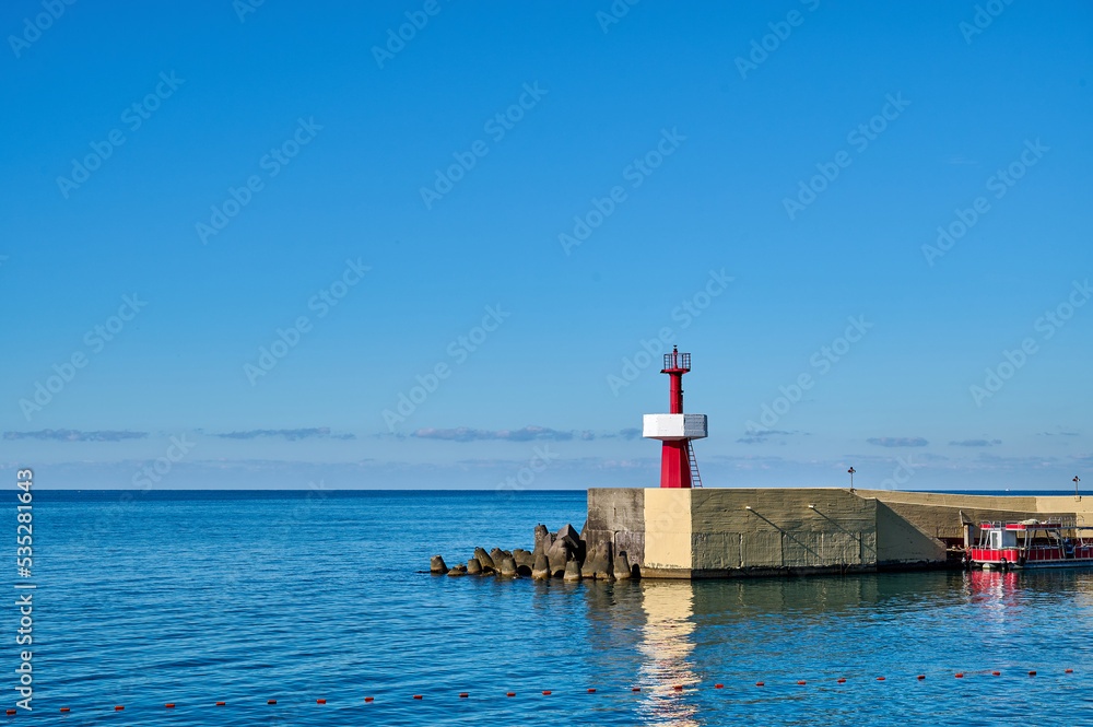 Little red lighthouse on the pier against the blue sky on sunny day, copy space