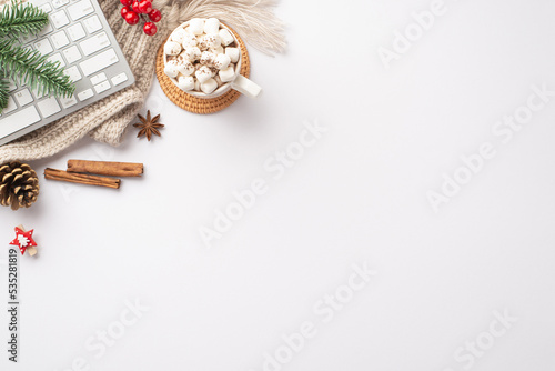 Winter concept. Top view photo of keyboard mug of hot drinking with marshmallow decorative clip pine cone fir branch mistletoe cinnamon sticks anise and cozy knitted plaid on isolated white background