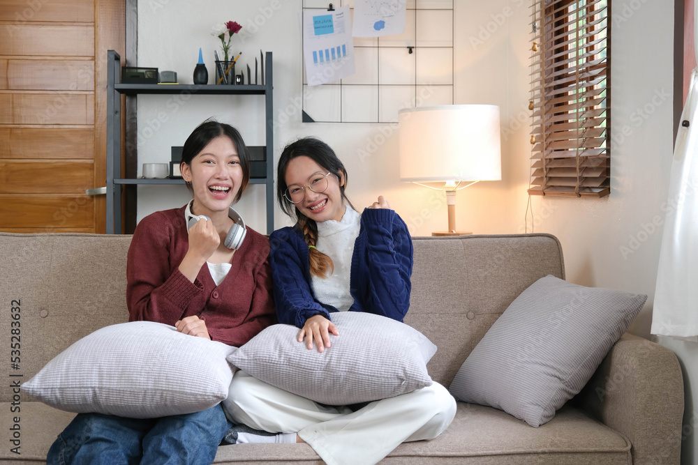 Obraz premium Two Young woman cheering together for sport on TV in cozy living room at home.