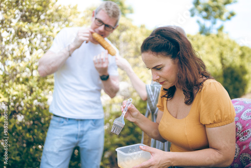 Happy family cheering with barbecue dinner outdoor - Group of people having fun at weekend meal - BBQ Food, taste and summer concept, Man cooking meat on barbecue grill at summer party