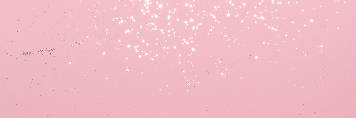 Sparkling silver glitter on pink background banner texture. Abstract holiday blurred lights header. Wide screen wallpaper. Panoramic web banner with copy space for design