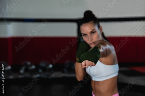 Young woman or girl mixed martial arts boxer fighter training in the octagon cage. Female bare knuckle boxing workout for new competition in MMA or Brazillian Jiu Jitzu.