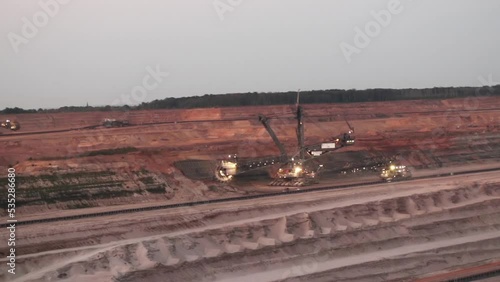 open pit bucket-wheel excavator with lights on mining brown coal at Garzweiler Germany in the morning in front of a geological cross-section