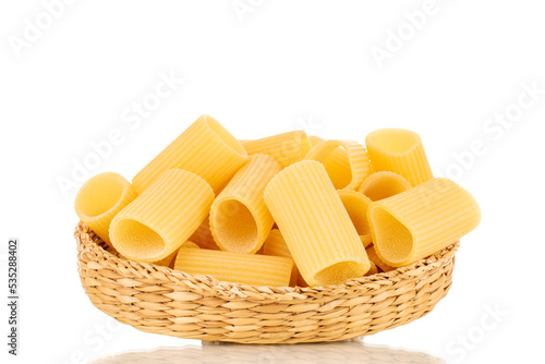 Several raw yellow cannelloni in a straw plate, macro, isolated on white background.