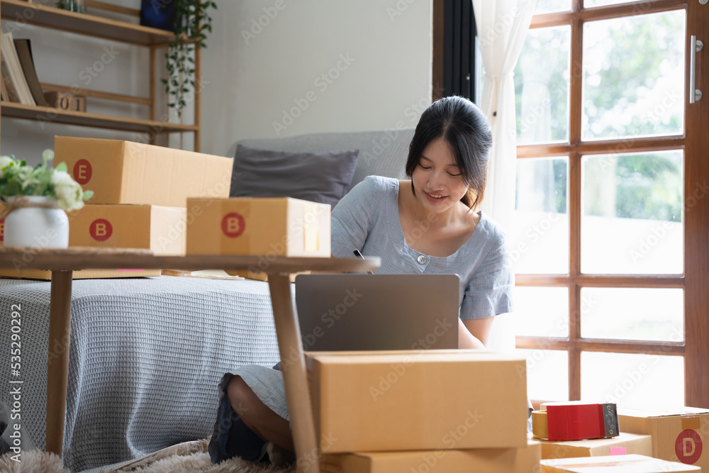 Start up small business, SME female owner checking order online to prepare to pack a box of goods for sale to customers, sme business idea. Start up small business, SME female owner checking order online to prepare to pack a box of goods for sale to customers, sme business idea.