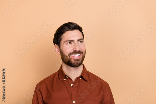 Portrait of satisfied nice young man toothy smile look interested empty space isolated on beige color background © deagreez