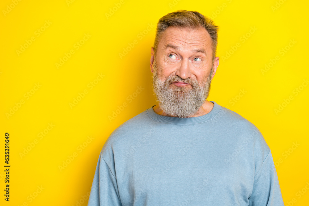 Photo of suspicious funny man pensioner dressed blue pullover looking empty space isolated yellow color background