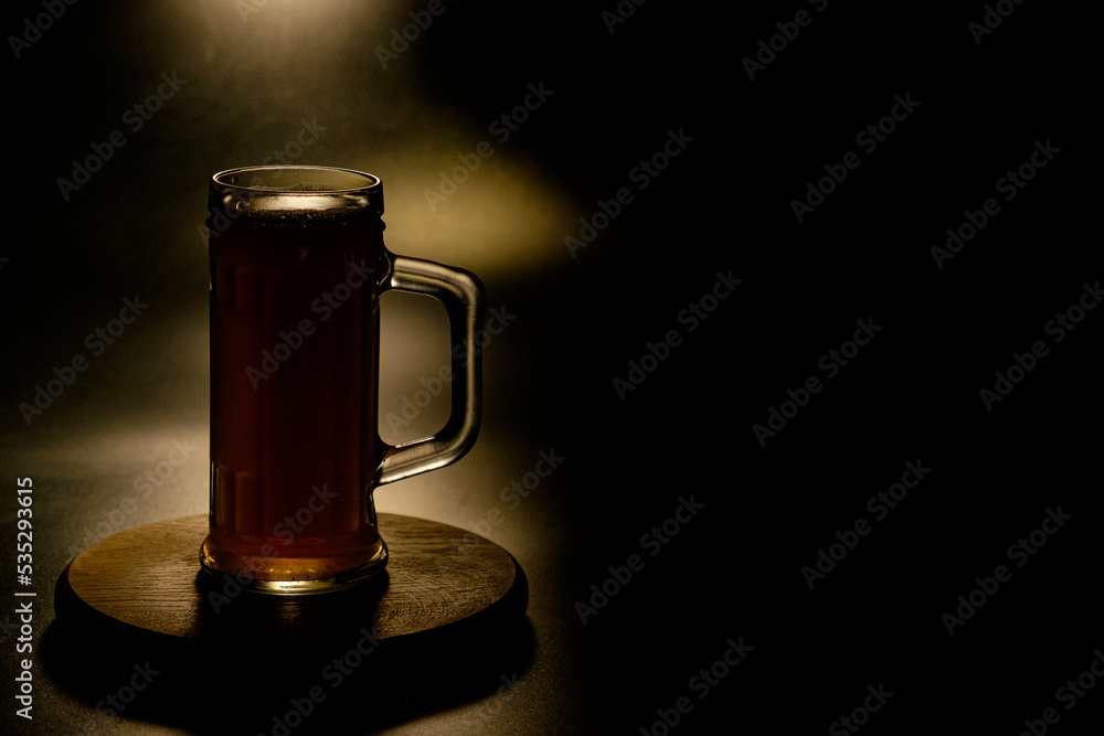 A glass of beer in the backlight , isolated on black smoke background . With space for text  - obrazy, fototapety, plakaty 