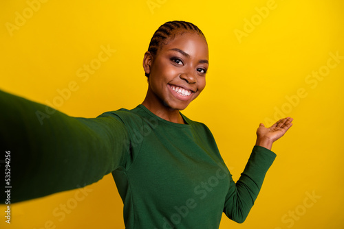 Photo of charming cute young woman wear green shirt recording self video inviting arm come isolated yellow color background photo