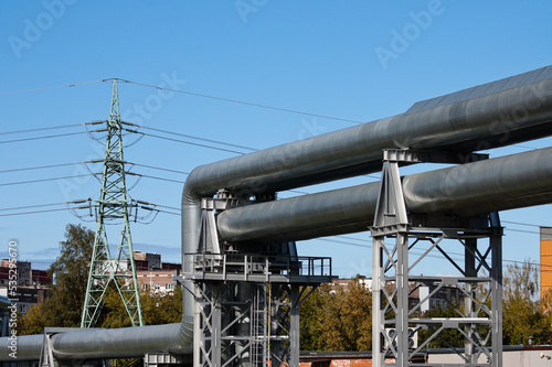 pipeline and power lines, in the photo pipelines and power line support on the background of the blue sky of the buildings of the city