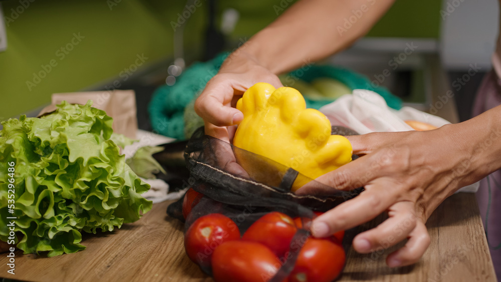 Woman takes fresh squash out of mesh bag with vegetables Woman takes fresh squash out of mesh bag with vegetables