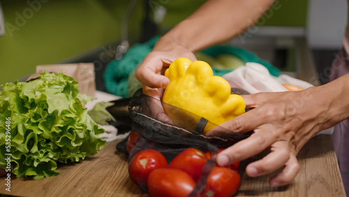 Woman takes fresh squash out of mesh bag with vegetables