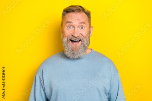 Photo of cute impressed man pensioner dressed blue pullover smiling open mouth isolated yellow color background