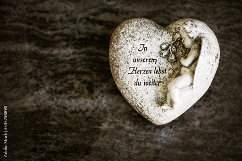 Herz auf Grab mit Schrift "In unseren Herzen lebst du weiter"