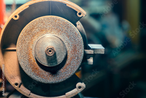 Grinding wheel on a grinder close-up on a blurred background. Machine for sharpening tools and parts. Abrasive nozzle