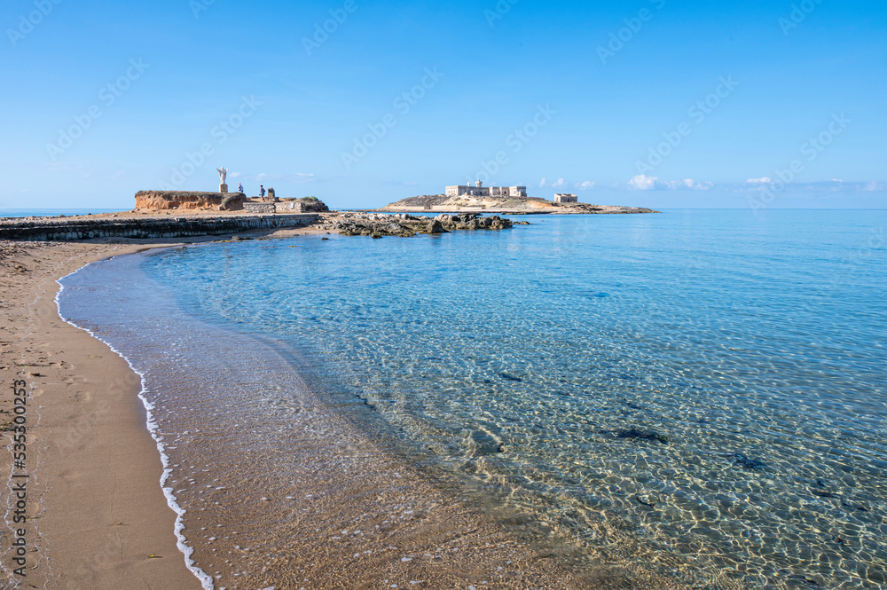 The beautiful Beach of Correnti with transparent and blue water in Portopalo in Sicily with the Island of Correnti in background