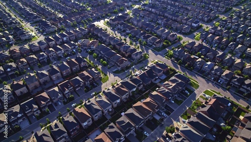 Aerial view of middle class residential houses at summer evening. American neighbourhood suburb. Residential houses and homes build in strong pattern to each other. Real estate.