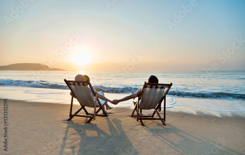Couple sunbathing on a beach chair.