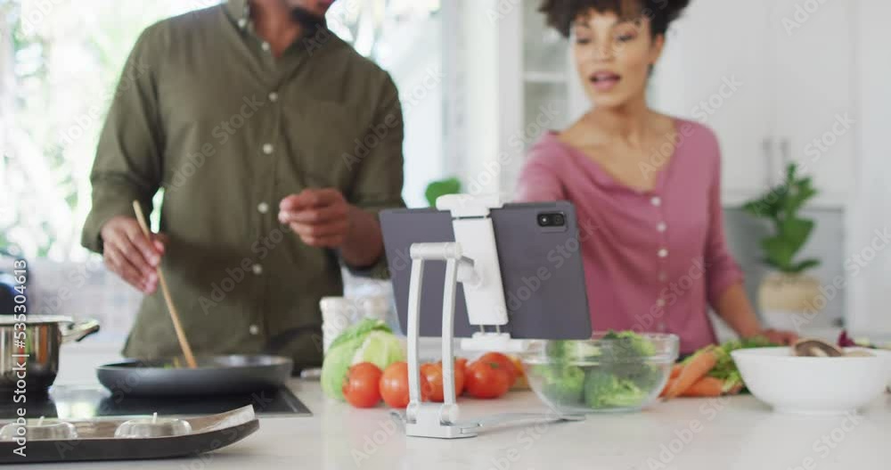 Happy african american couple cooking and using tablet in kitchen Happy african american couple cooking and using tablet in kitchen