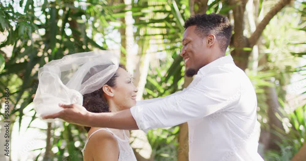 Happy married african american couple unveiling veil and smiling