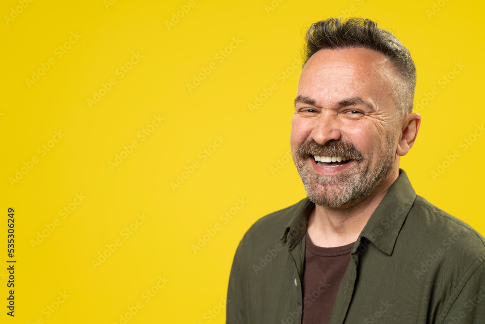 Obraz premium Happy attractive handsome mature man with beard smiling isolated over yellow background. Active Positive middle-age person lifestyle concept.
