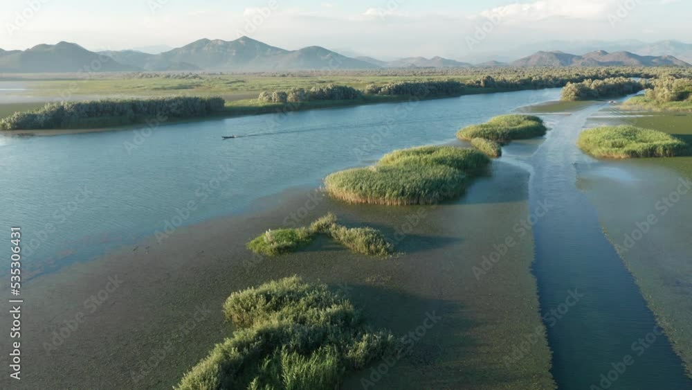 Small green islands covered with grass in blue water of Lake Skadar in Montenegro. Aerial drone view of tropical lagoon or river - a famous summer vacation travel destination. Small green islands covered with grass in blue water of Lake Skadar in Montenegro. Aerial drone view of tropical lagoon or river - a famous summer vacation travel destination.